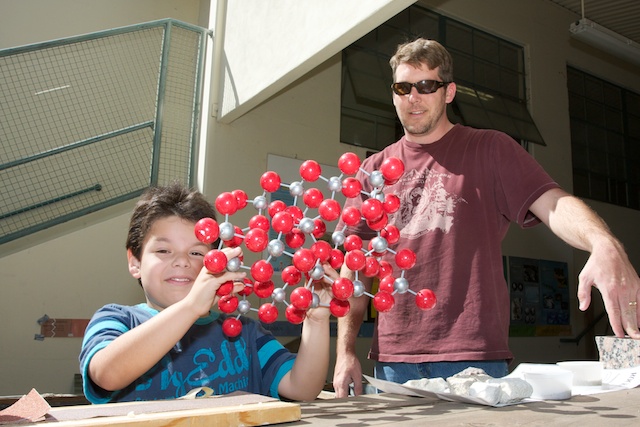 boy with atom model on table outside